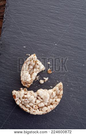 Broken crispbread on stone plate. Dark background. Copyspace for text. Top view.