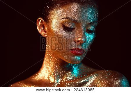 Portrait of Beautiful Woman with Sparkles on her Face. Girl with Art Make-Up in Color Light. Fashion Model with Colorful Makeup