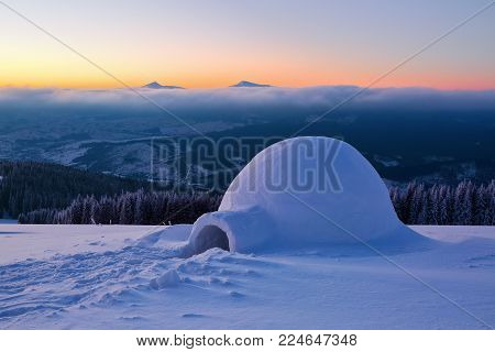 Marvelous huge white snowy hut, igloo  the house of isolated tourist is standing on high mountain far away from the human eye. Beautiful winter landscape.