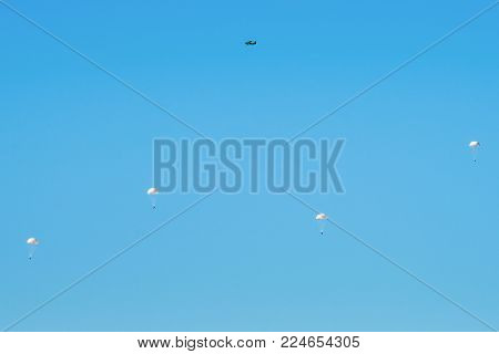 Airborne Troops A Mass Parachute Drop Over The Sea. On A Blue Sky Background.