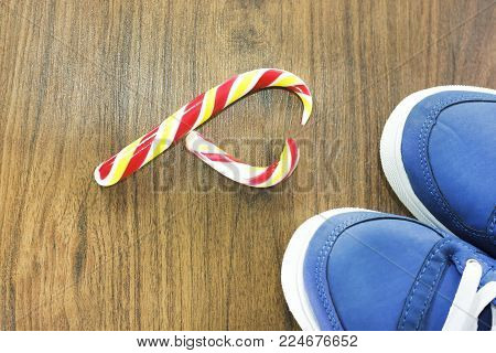Blue sneakers. wooden background. Candy in the shape of a broken heart. It is expected that you will give up what you like and from an excess lifestyle.