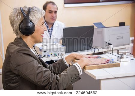 Senior woman checking her health status at the clinic, undergoing quantum and bioresonant medical exam