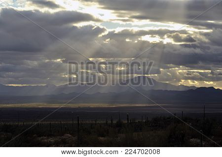 Silver Lining Sun Rays through the clouds with Saguaro Cactus, Desert and Mountains in the background.