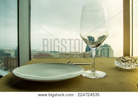 Empty wine glass on the table in front of a window. Close up shot.