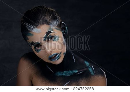 A woman with cloroful make up and painted art on a neck.