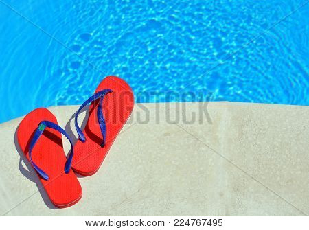 Pair of red flip-flops on the swimming pool.