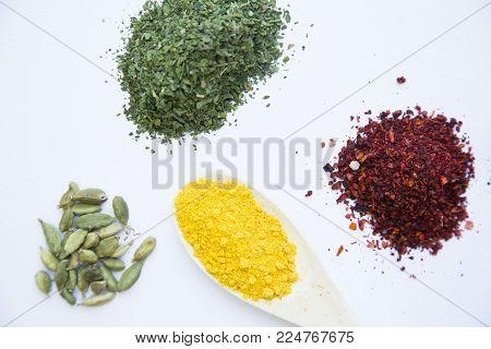 Indian and Asian Spices. Dry herbs, crushed red pepper, curcuma on wooden spoon and dry beans on white background, top view