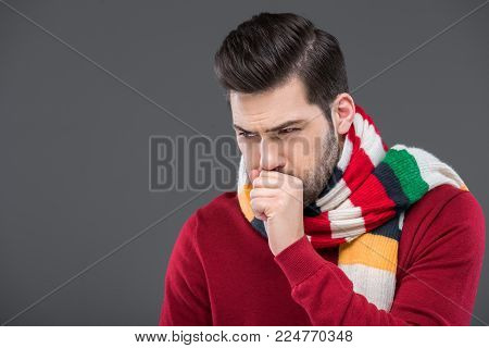sick man coughing in warm scarf, isolated on grey