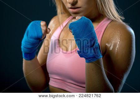 Boxing woman. Young woman fighter ready to fight. Strong woman. Female hands wrapped in boxing bandage over dark background