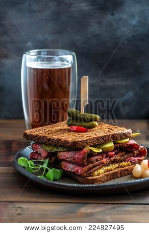 Delicious huge pastrami sandwich with beer and pickle, close view