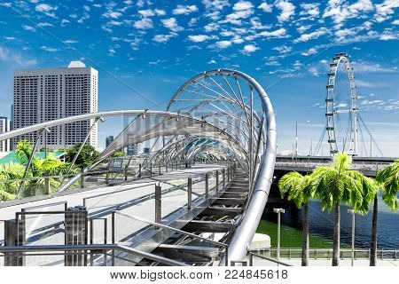 Singapore city landscape at day blue sky. Pedestrian DNA bridge and ferris wheel Flyer at Marina Bay view. Urban cityscape