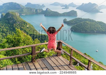 Woman tourist jumping with happy it has reached the peak mountain to see the beautiful natural landscape of sea from view point of Ko Wua Ta Lap island in Mu Ko Ang Thong, Surat Thani, Thailand