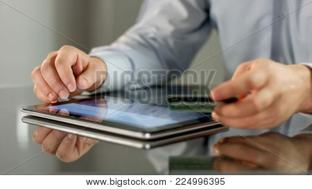 Male hands making online noncash payment on tablet, inserting bank card details HD