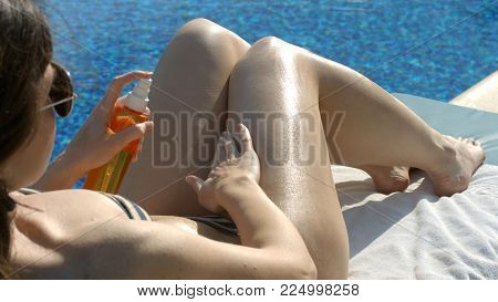 Woman spraying tanning oil on body, skin nourishment, beauty care and protection HD