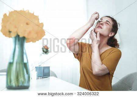 Young Woman Using Eye Drops While Having Allergy To Flowers