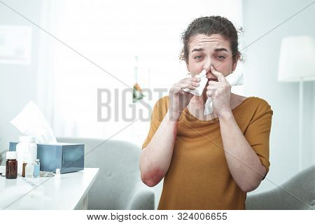 Curly Woman Wearing Orange Shirt Using Nose Spray Having Allergy