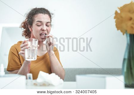 Woman Holding Glass Of Water While Taking Allergy Medication
