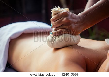 Portrait Of Young Beautiful Woman Lying On A Wooden Table In Spa Environment Flowers And Candles