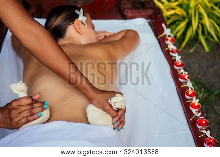 Portrait Of Young Beautiful Woman Lying On A Wooden Table In Spa Environment Flowers And Candles