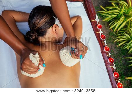 Portrait Of Young Beautiful Woman Lying On A Wooden Table In Spa Environment Flowers And Candles
