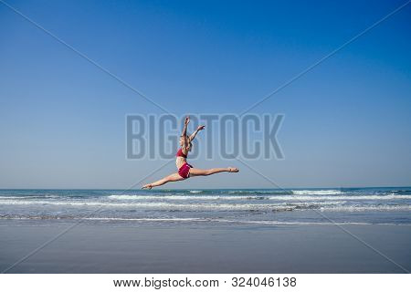 Gymnast Girl Doing Splits Grand Jete In The Air. Beautiful Young Fit Gymnast Woman Working Out, Perf