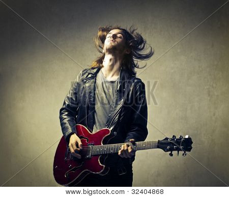 Młody mężczyzna grający na gitarze i headbanging