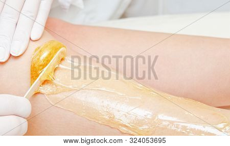 Cosmetologist Beautician Waxing Female Legs In The Spa Center Beauty Salon Closeup. Cosmetology Conc