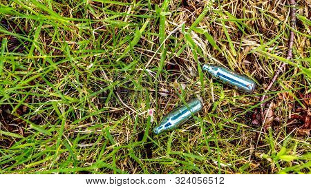 Empty Bulbs Of Nitrous Oxide Or Laughing Gas On The Grass In A Public Park, Hippie Crack Is Used As 