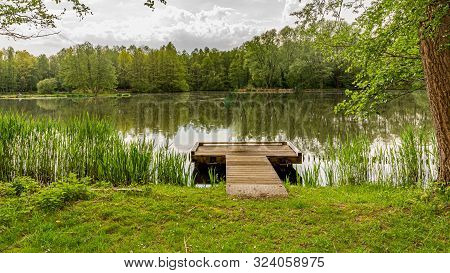 Fishing Platform On The Lake In The Middle Of The Forest Surrounded By Trees And Green Vegetation Wi