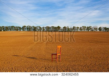 Old Wooden Chair  On The Empty Field In Autumn. The Field After Harvesting In Sunny Day.czech Republ