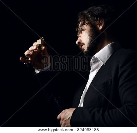 Brutal Man In Glasses With Beard And Modern Hairstyle Perfumer Examines Small Bottle Of Perfume Frag