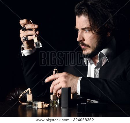Focused Brutal Bearded Man With Modern Hairstyle In Stylish Official Suit Perfumer Examines Small Bo