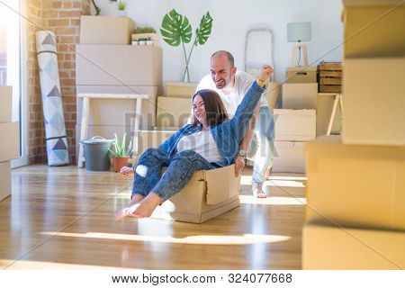 Funny and crazy couple having fun riding a cardboad box as a car, smiling happy and lauging at new home