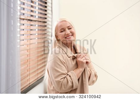 Portrait Of Happy Mature Woman Near Window Indoors