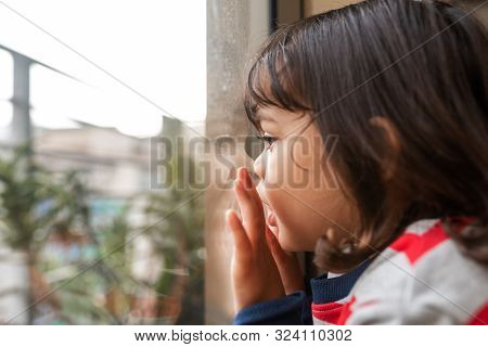 Cute Littel Girl Looking Through A Window At Home