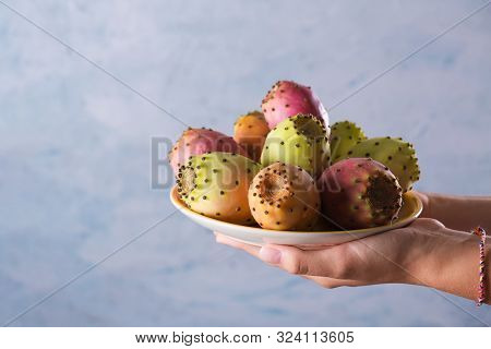 Female Hands Hold A Plate With Ripe Fresh Fruits Of Prickly Pear On A Gray Background, Selective Foc