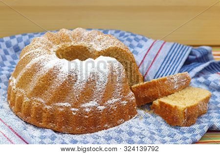 Traditional Bundt Cake With Two Cake Slices On A Retro Kitchen Towel, Close-up With A Bright Wooden 