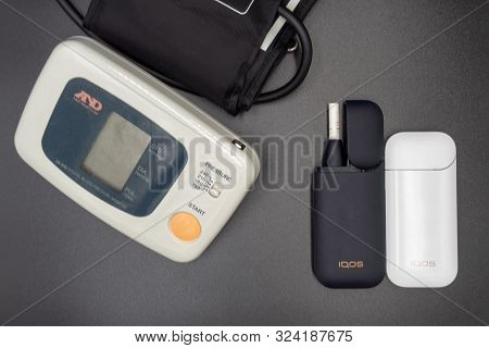 Blood Pressure Tonometer And Iqos On A Gray Background. The Concept Of Health Damage From Smoking An