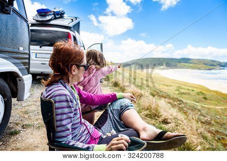 Motorhome Rv Or Campervan Is Parked On A Beach. Family On Vacation Is Sitting Outsides On Camping Ch