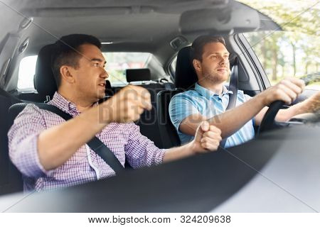 driver courses and people concept - car driving school instructor teaching young man to drive
