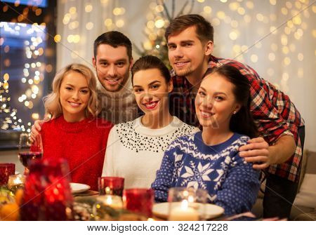 holidays and celebration concept - happy friends having christmas dinner at home