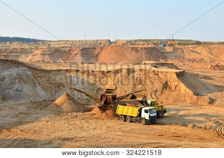 Wheel Front-end Loader Unloading Sand Into Heavy Dump Truck. Crushing Plants, Machines And Equipment