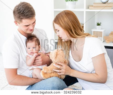 Family play with teddy bear in light room
