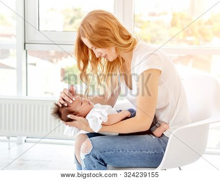 Young mother hugging cute baby at home