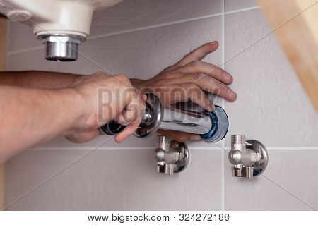Closeup Male Plumber's Hand Fixing Sink In Bathroom With Tile Wall. Professional Plumbing Repair Ser