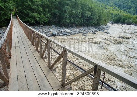 Hanged Rope Bridge Over The Fast Muddy River