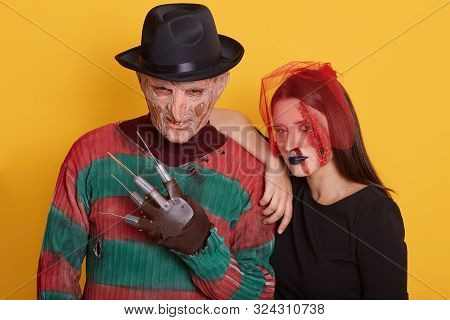 Close Up View Of Young Couple Wearing Halloween Costumes, Woman And Man Looking Directly At Camera, 