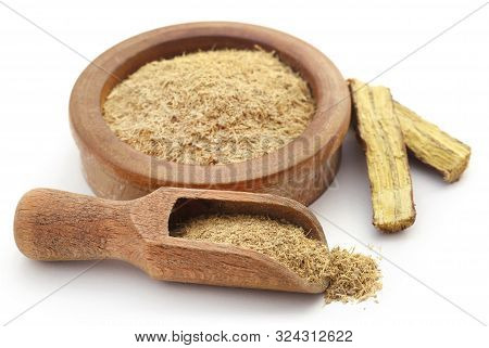 Liquorice With Powder In A Bowl And Wooden Scoop Over White
