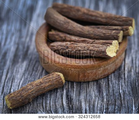 Liquorice Stick In Wooden Bowl On Textured Surface