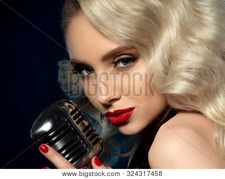 Portrait Of Pretty Blond Female Singer Holding Microphone
